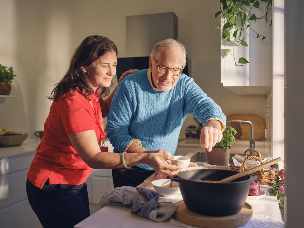 Older man and caregiver preparing a meal together, illustrating the benefits of Companion Care.